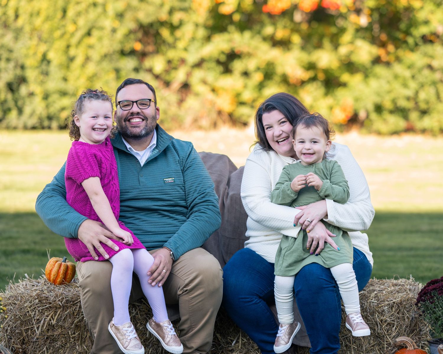 Family of four smiling outdoors at a family photoshoot in the Merrimack Valley