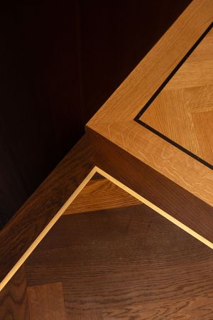 Close-up of elegant wood parquet flooring with dark inlay borders and geometric corner detail in warm oak tones.