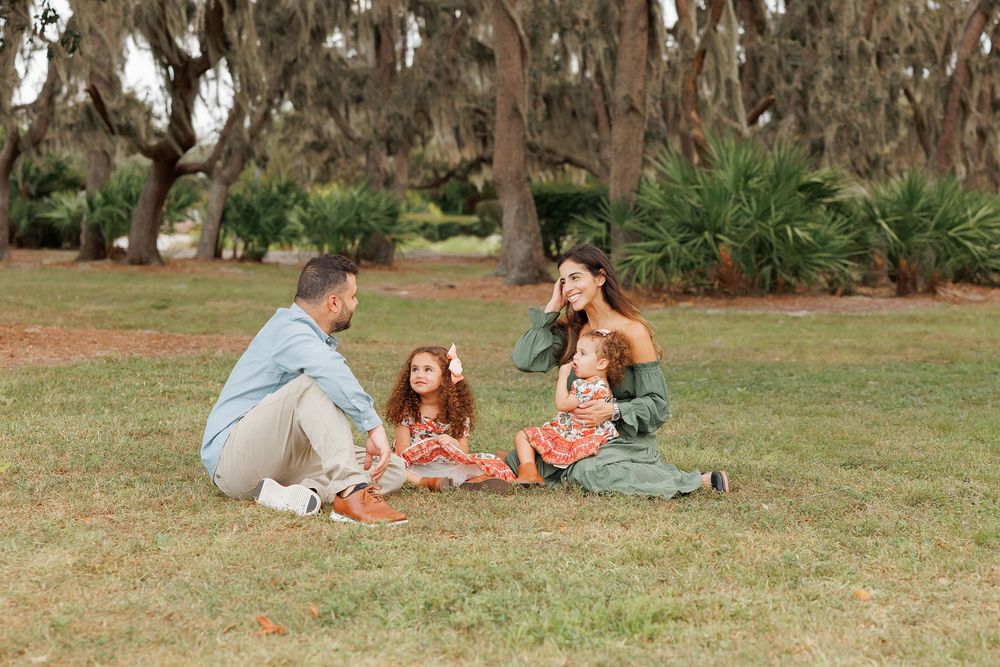 Family enjoying a relaxing day together on blankets spread out on grass in a park setting.