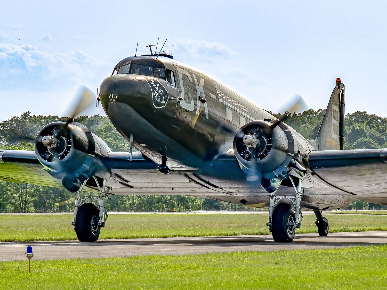 Vintage WWII Douglas DC-3 military aircraft taxiing on runway at airshow, featuring twin propeller engines and classic olive drab livery.