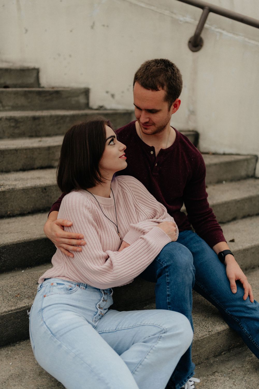 A couple in cozy sweaters sitting together on urban steps during a Rome GA portrait session by Ella Monroe Photography