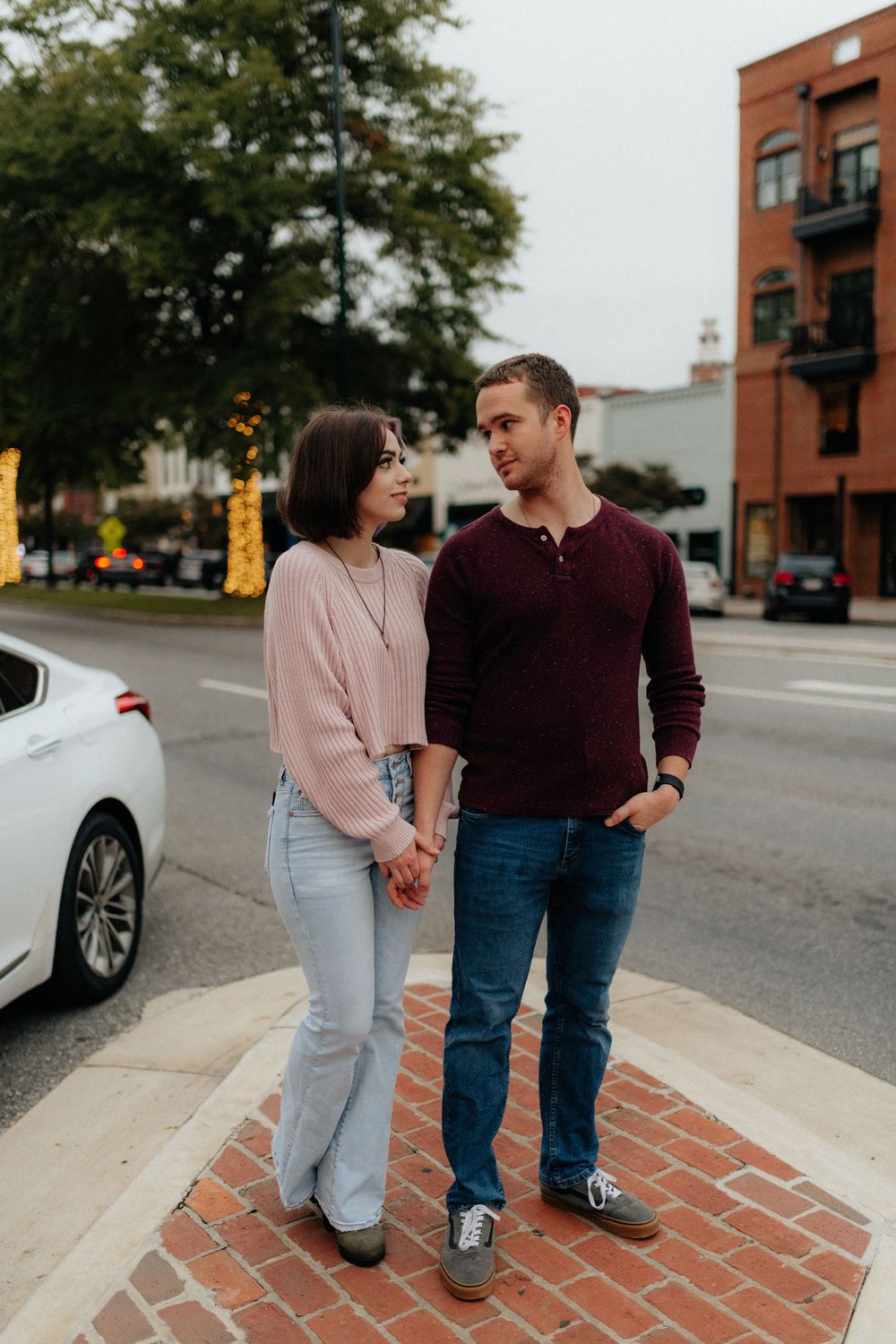 A young couple looking at each other on a street corner during a lifestyle couples session in Rome, GA by Ella Monroe Photography.