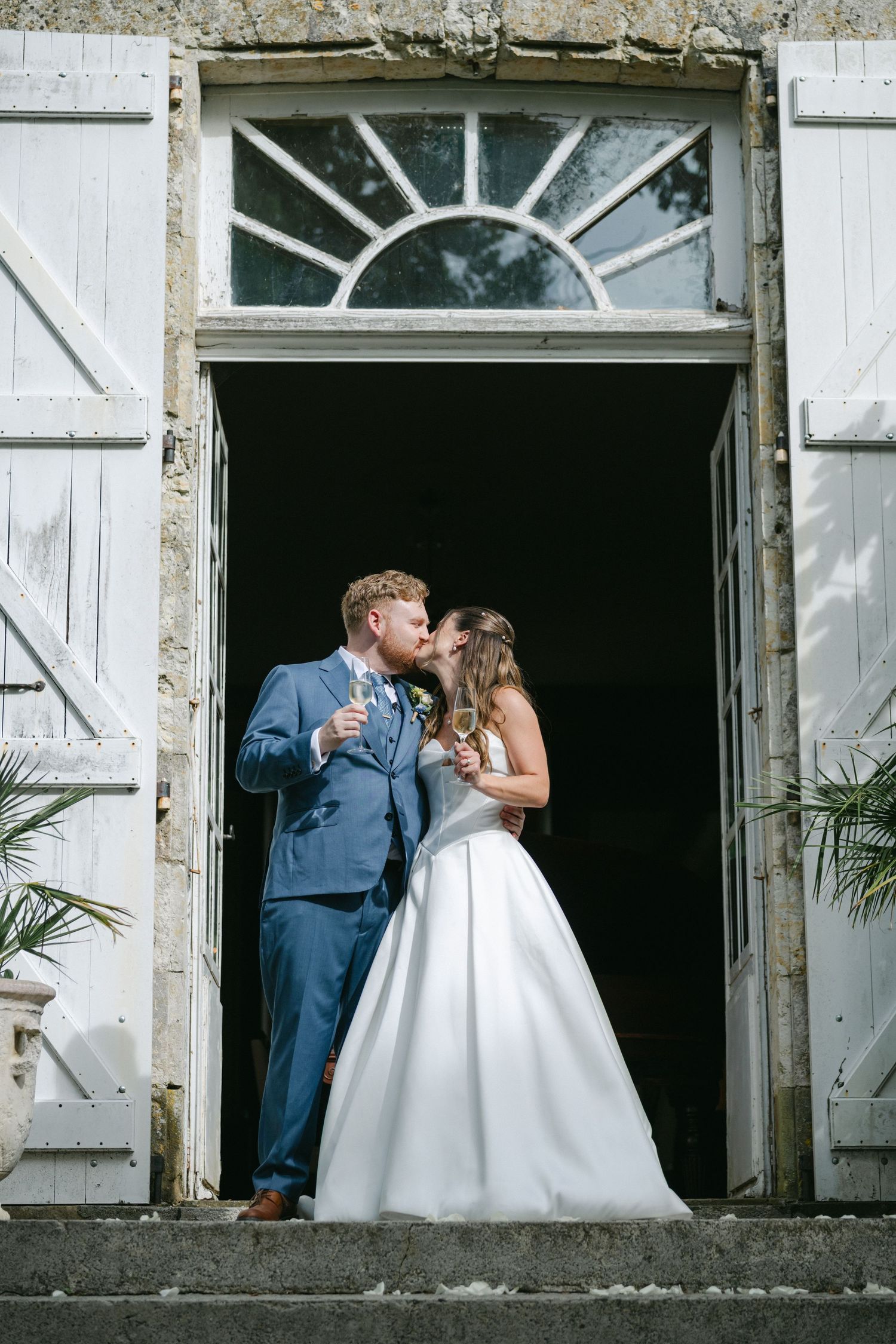 Bride and groom share a romantic kiss outside church while guests celebrate with confetti at their wedding reception.