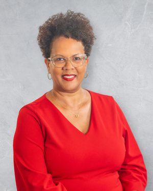 Professional woman in red top and clear glasses smiling confidently against a gray background.  Quad Cities Photography