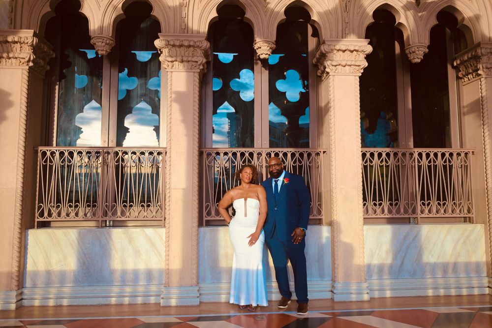 Couple posing elegantly in white dress and navy suit inside ornate Venetian-style architecture at The Venetian Las Vegas.