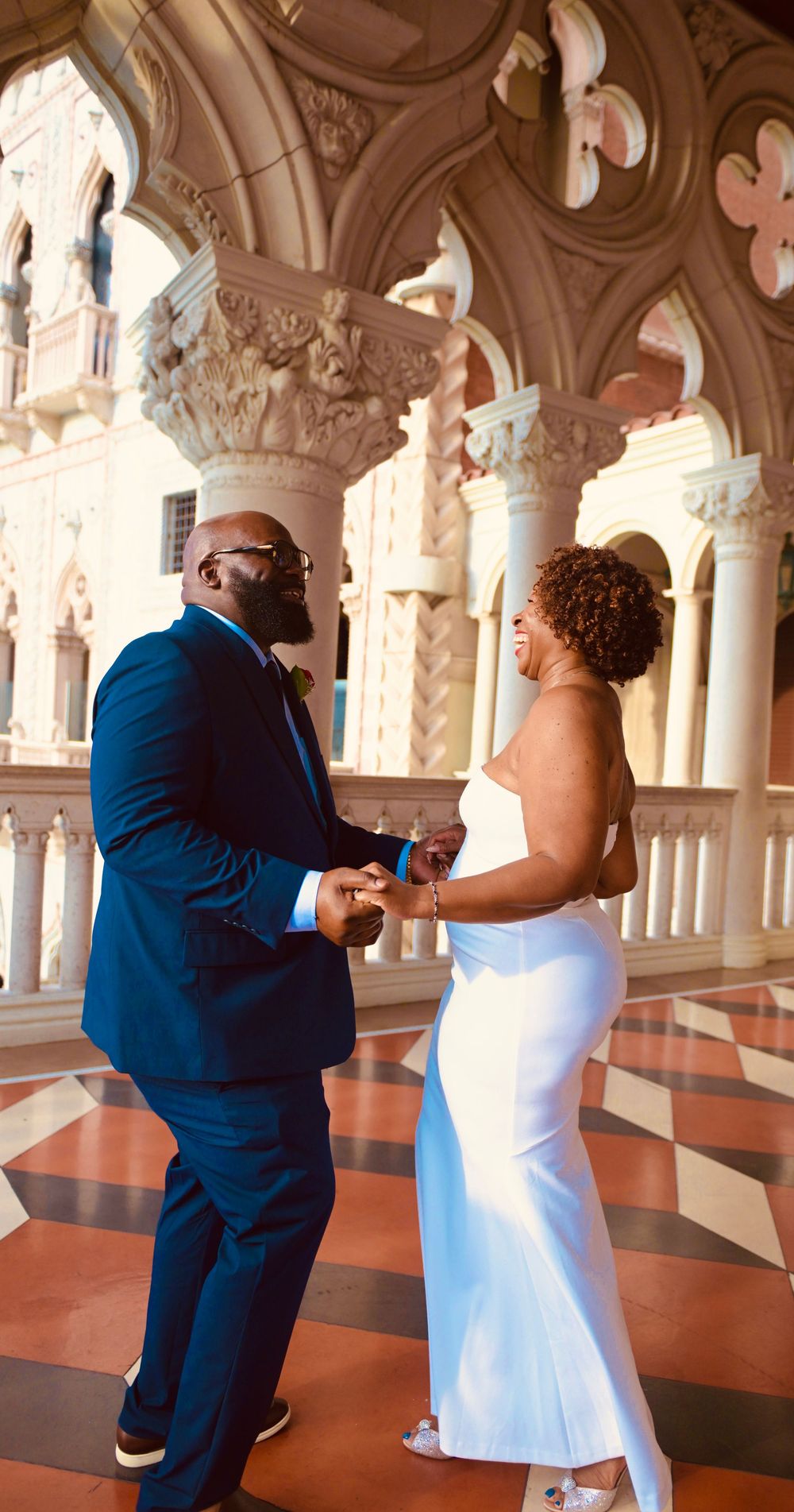 Bride and groom laughing together in ornate Venetian-style architecture at a Las Vegas wedding.