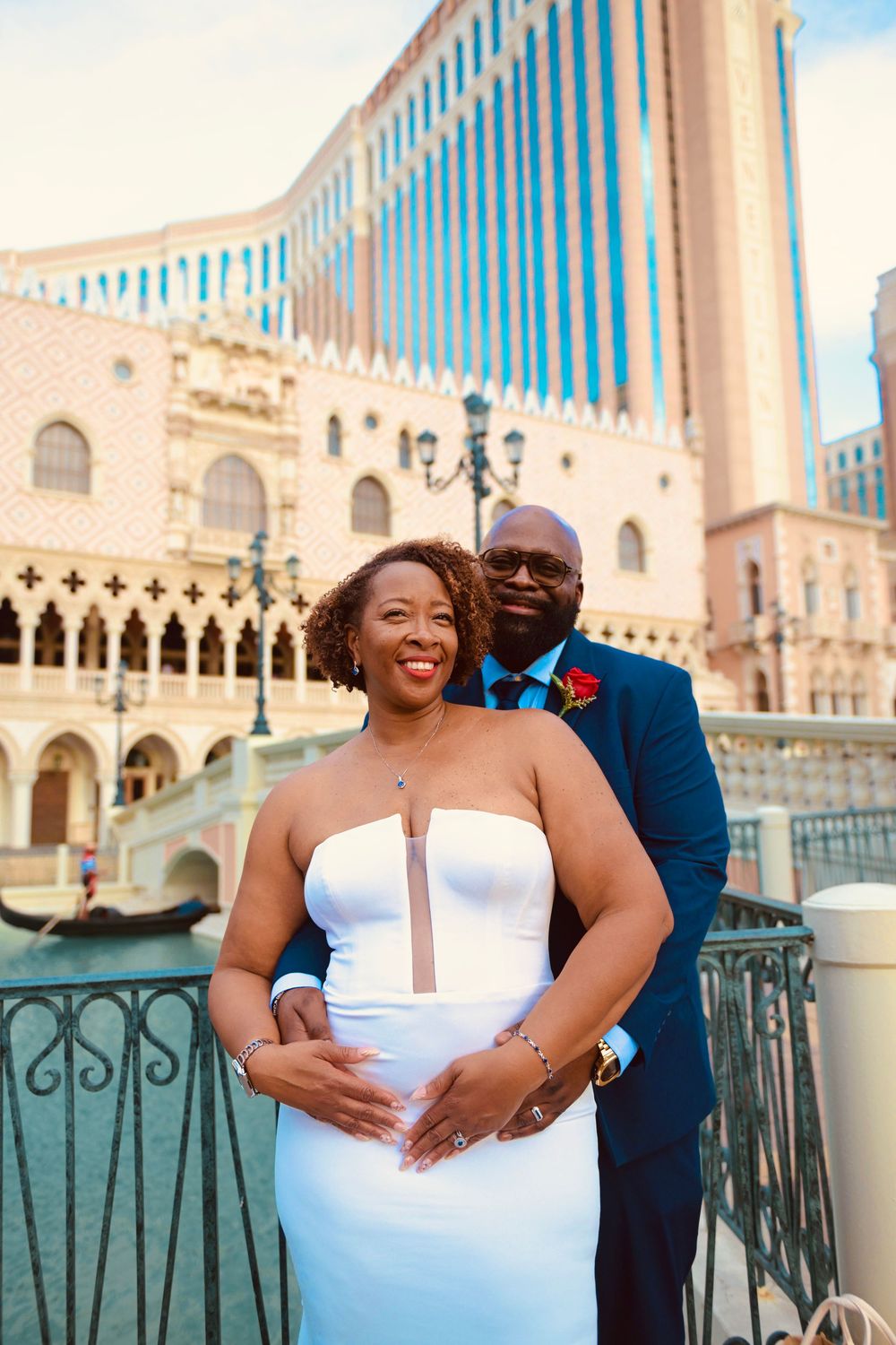 Couple in wedding attire posing in front of The Venetian Las Vegas with gondola in background.