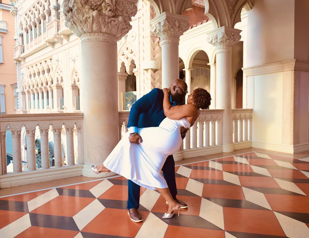 A couple shares a romantic dip kiss on a marble checkered floor surrounded by ornate columns at The Venetian Las Vegas.