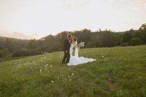 Bride and groom share a romantic moment in a lush green meadow at golden hour during their outdoor wedding.