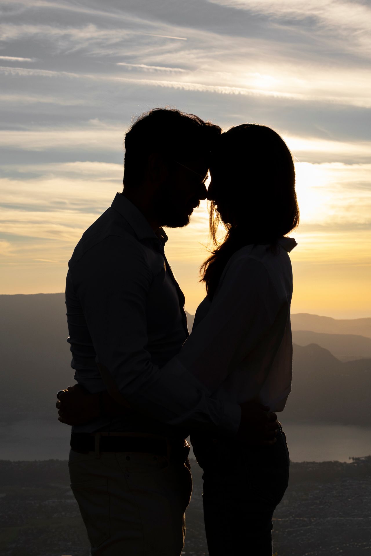 Silhouette d’un couple front contre front devant un coucher de soleil sur les montagnes, Savoie