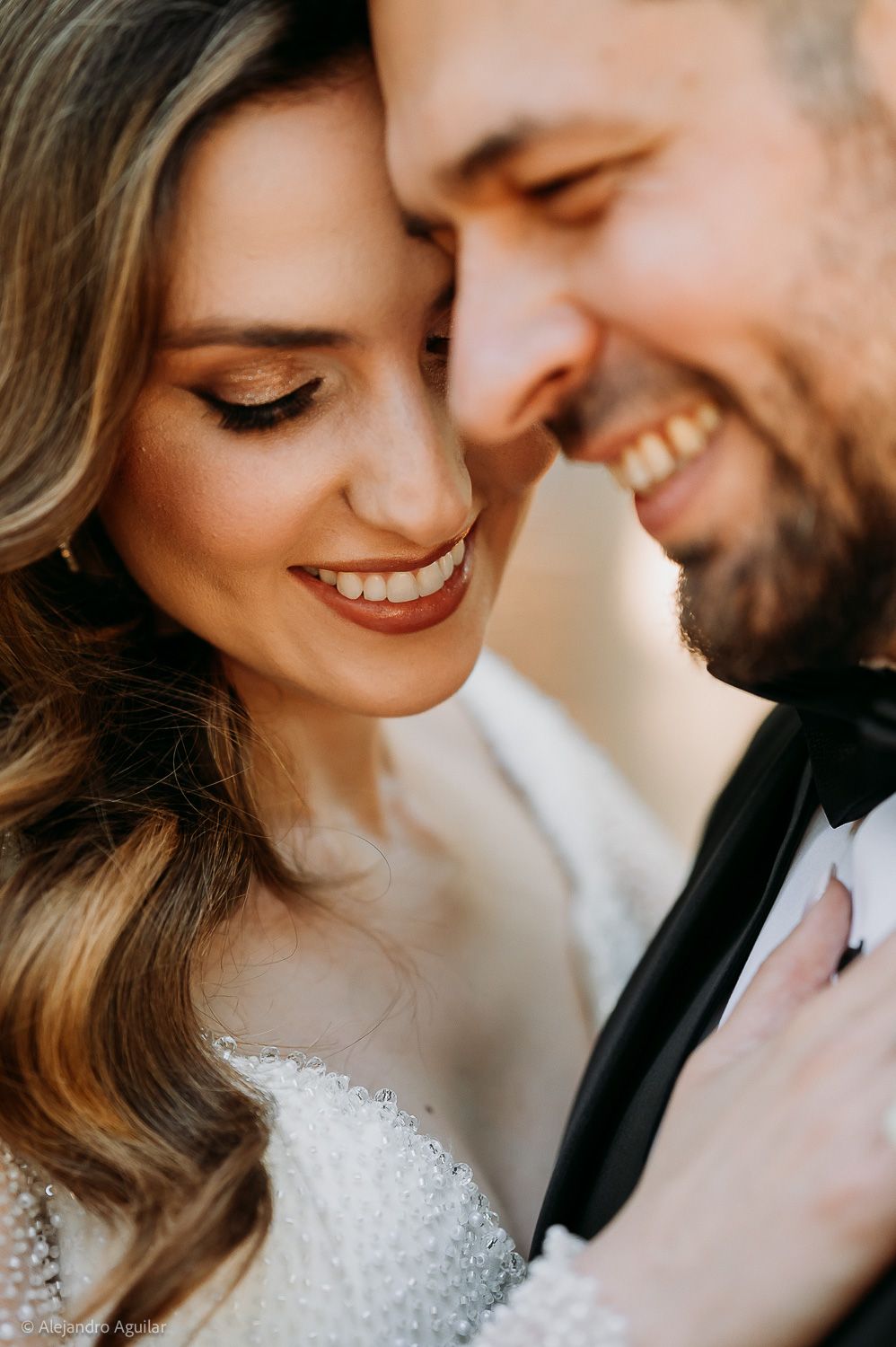A joyful bride and groom share an intimate moment, smiling closely together on their wedding day.