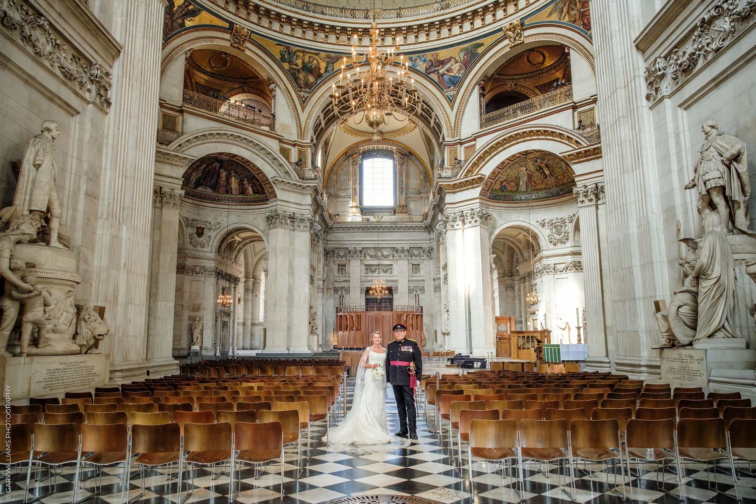 Bride and groom walking down the aisle of St Paul's Cathedral, London, with ornate baroque architecture.