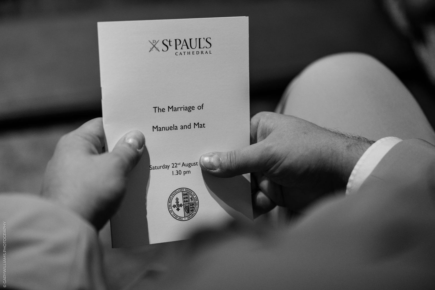 Hands holding a St. Paul's Cathedral wedding program for the marriage of Manuela and Mat on Saturday 21st August.