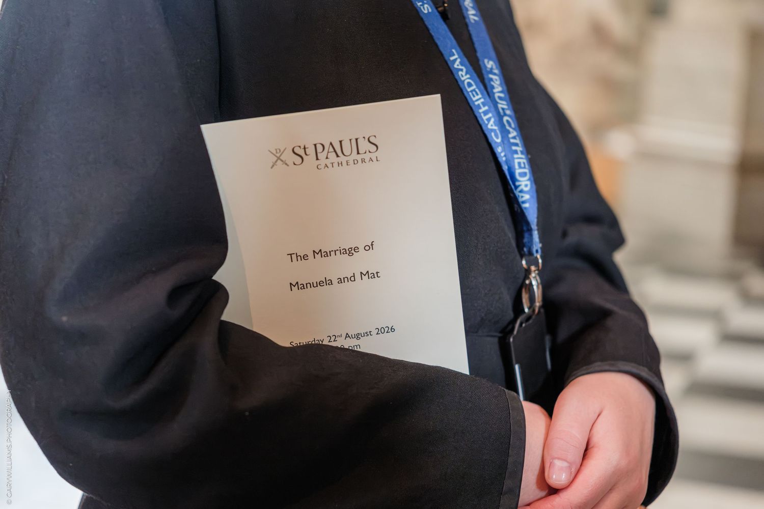 Person holding a St Paul's Cathedral wedding program for the marriage ceremony, with a blue lanyard visible.