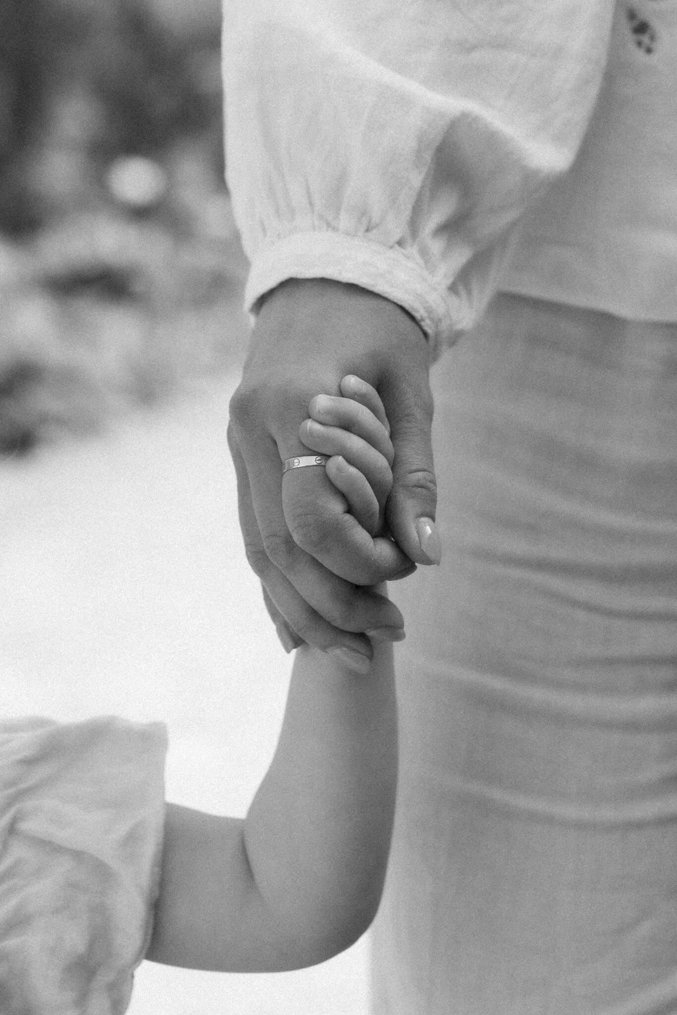 Timeless black and white photo of child holding mother’s hand during luxury portrait session in Brighton
