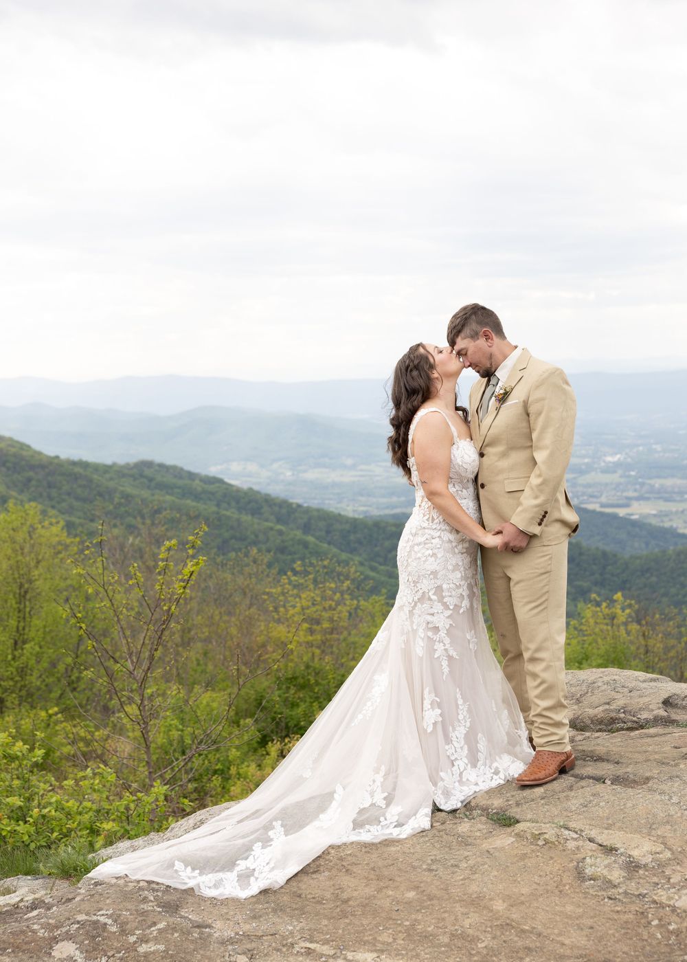Bride and groom share an intimate moment on a rocky cliff with stunning Shenandoah Valley mountain views.