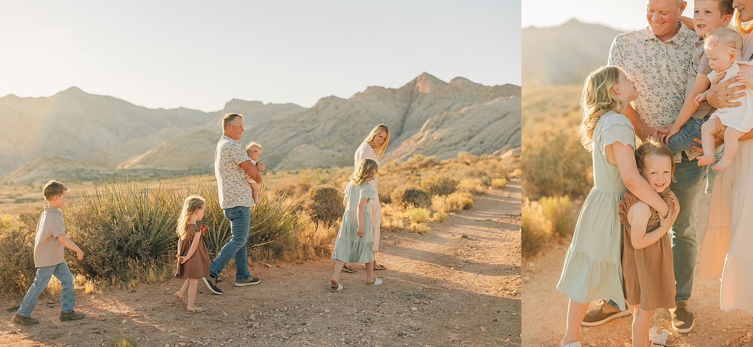 Family posing in golden desert landscape with mountains at sunset, children playing while parents hold baby in soft natural light.