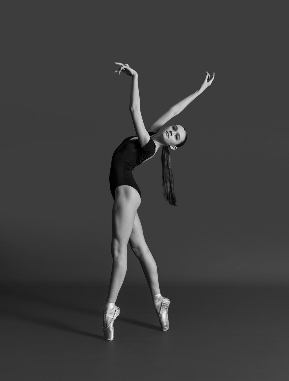 Black and white photo series of a ballet dancer performing graceful movements in pointe shoes against a dark background.