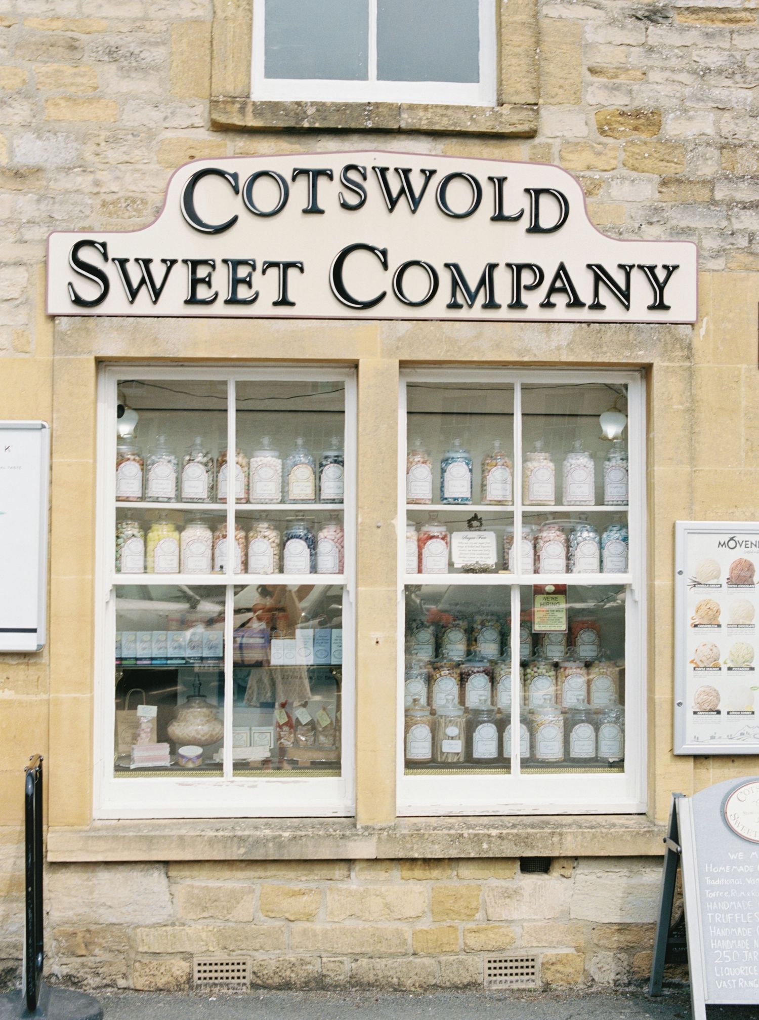Cotswold Sweet Company shop front with jars of sweets displayed in windows, traditional stone building, Bourton-on-the-Water.