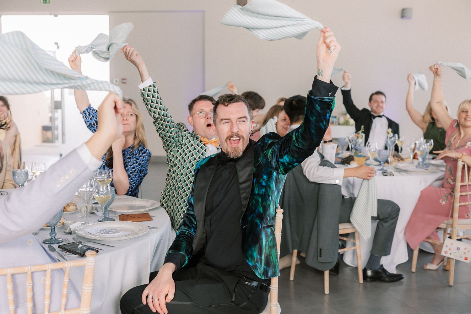 Wedding guests waving blue napkins during the lively reception celebration at Arriba by the Sea in Cascais, Portugal.