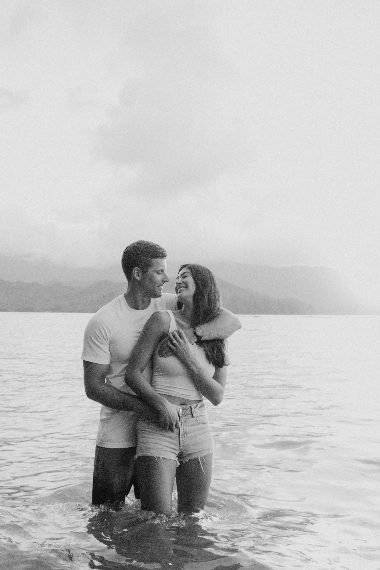Bride and groom embracing during romantic bridal portraits surrounded by the lush green mountains and breathtaking scenery of Hanalei Kauai.