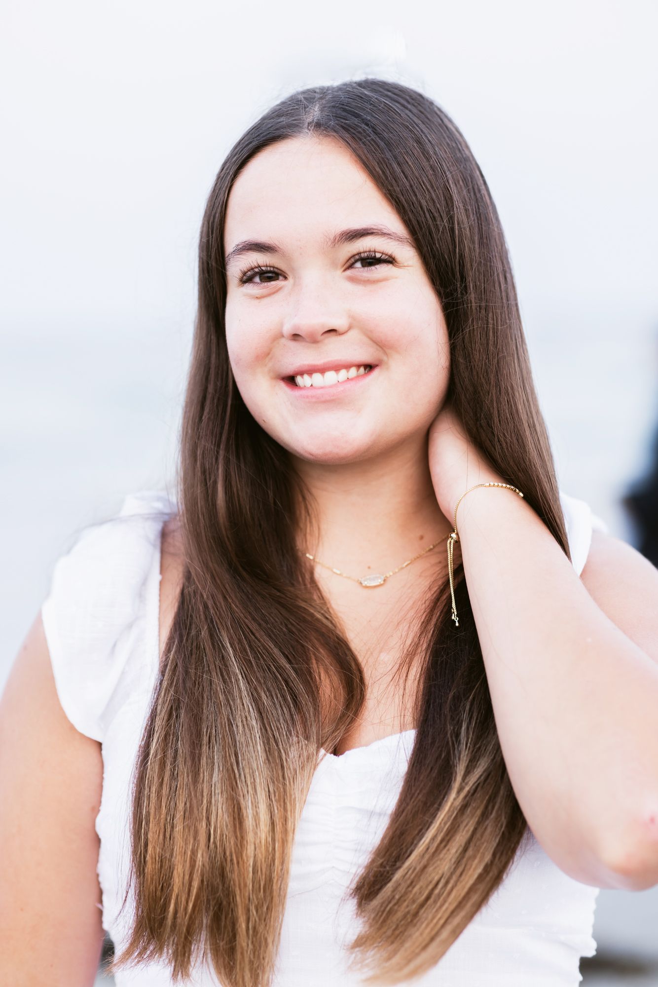 Brown hair senior girl wearing white poses at Good Harbor Beach for senior photos. North Shore senior photographer.