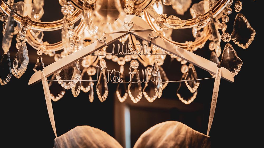 Crystal chandelier with elegant wedding dress hangers displayed beneath sparkling glass pendants.