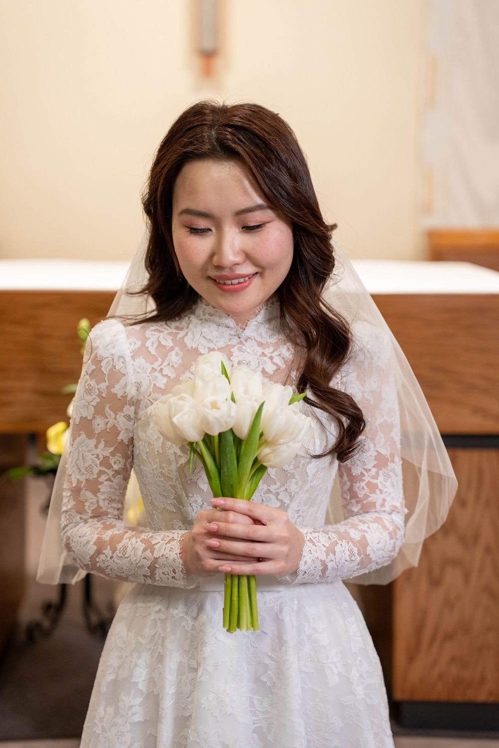 Bride looking down at her floral bouquet in front of the church altar in Tucson, Arizona, captured by N&D Media Production.