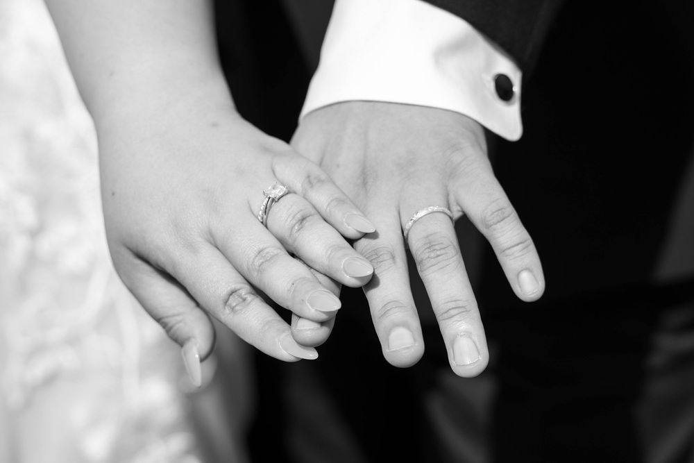 Black and white photo of bride and groom showing off wedding bands at The Hitching Post, captured by N&D Media Production.