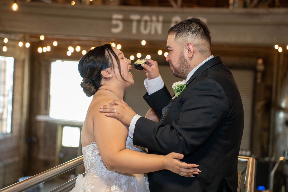 Playful cake cutting moment as groom feeds bride at The Hitching Post venue in Utah, captured by N&D Media Production.