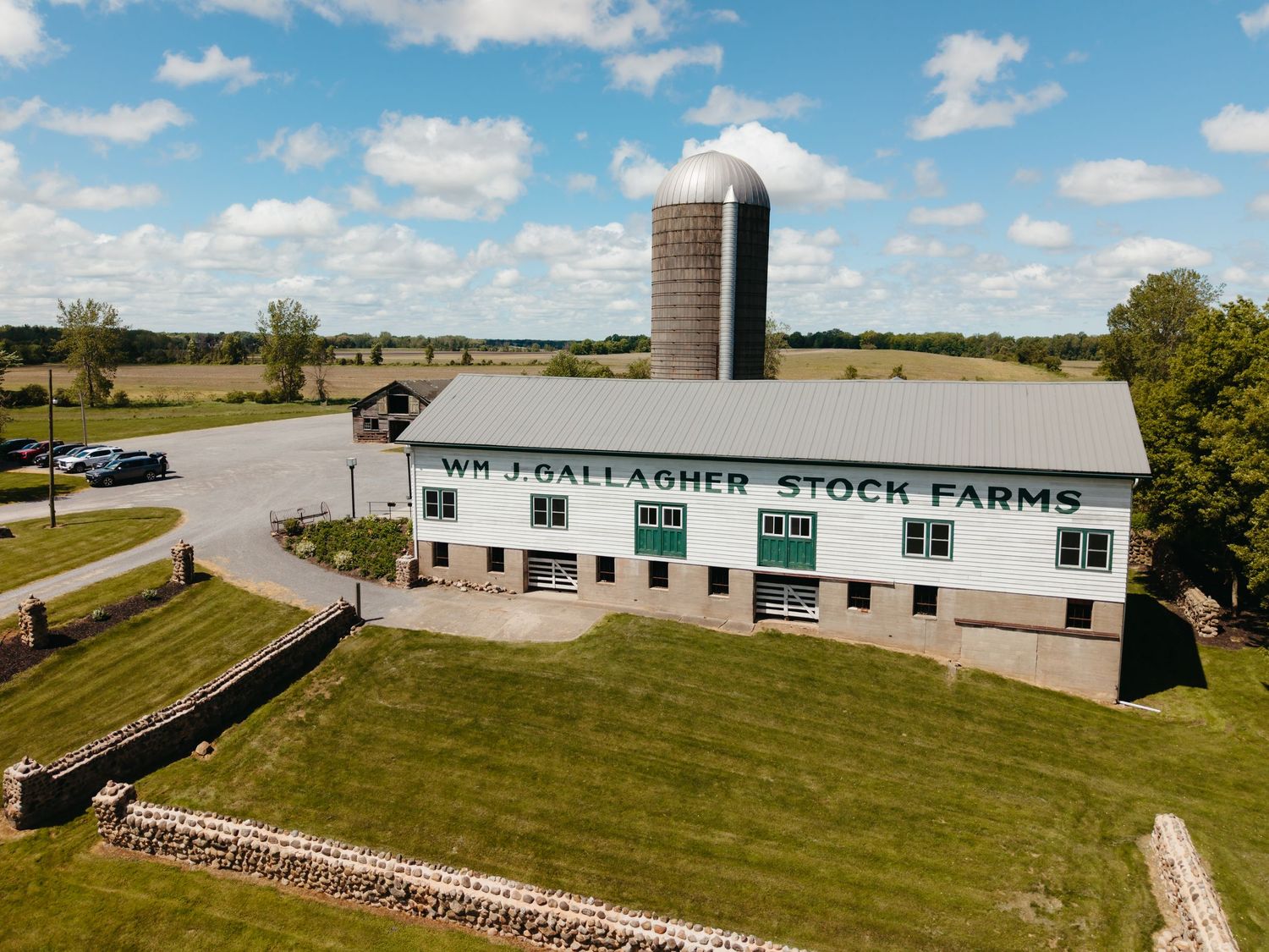 Aerial view of Wm. J. Gallagher Stock Farms white barn with silo surrounded by green fields.