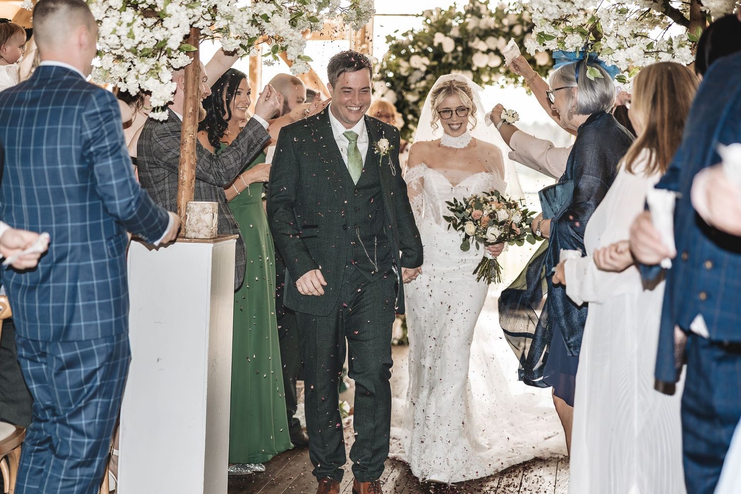 Wedding guests share a fun confetti moment with the bride and groom