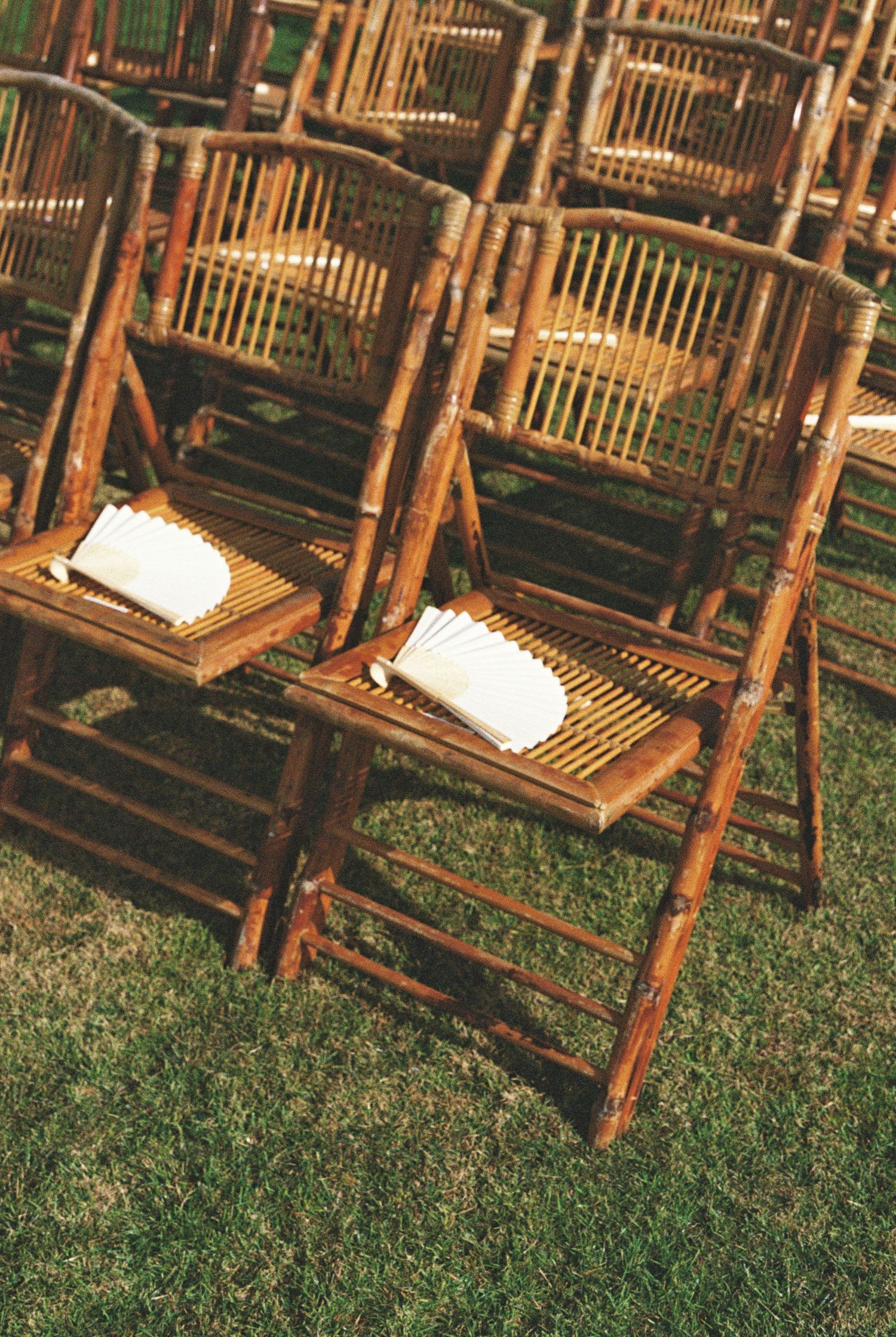 A couple's feet in the sand next to beach chairs, wearing coordinated white and cream outfits.
