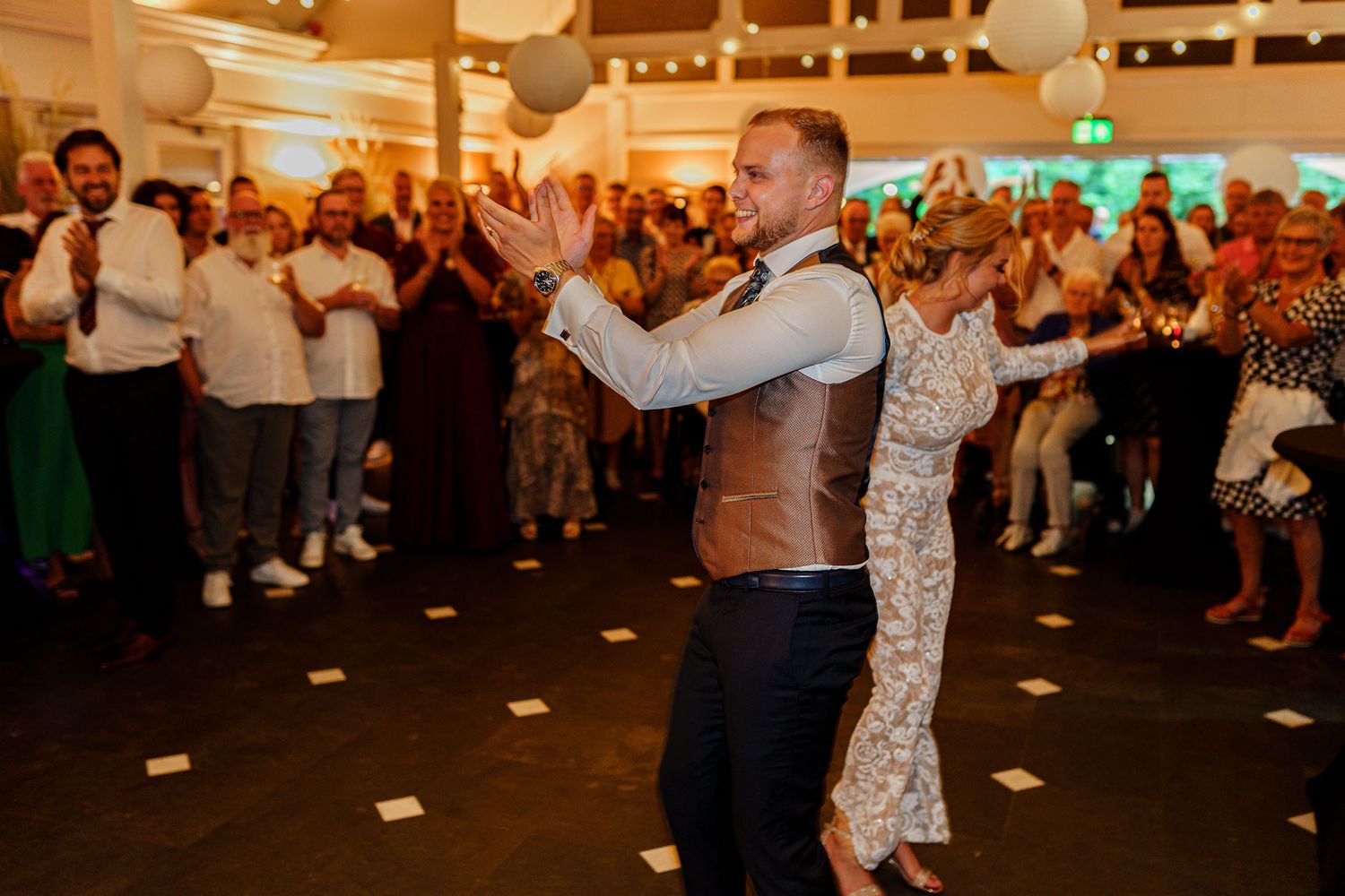 Festive wedding reception dance floor with glowing lights and decorative paper lanterns.