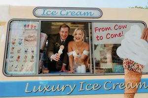 Bride and groom smiling in a luxury ice cream van window on their wedding day.