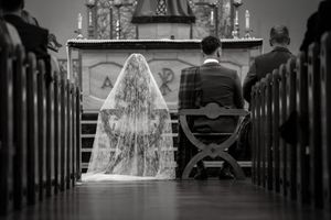 Black and white photo of a bride and groom kneeling at a church altar during a traditional wedding ceremony.