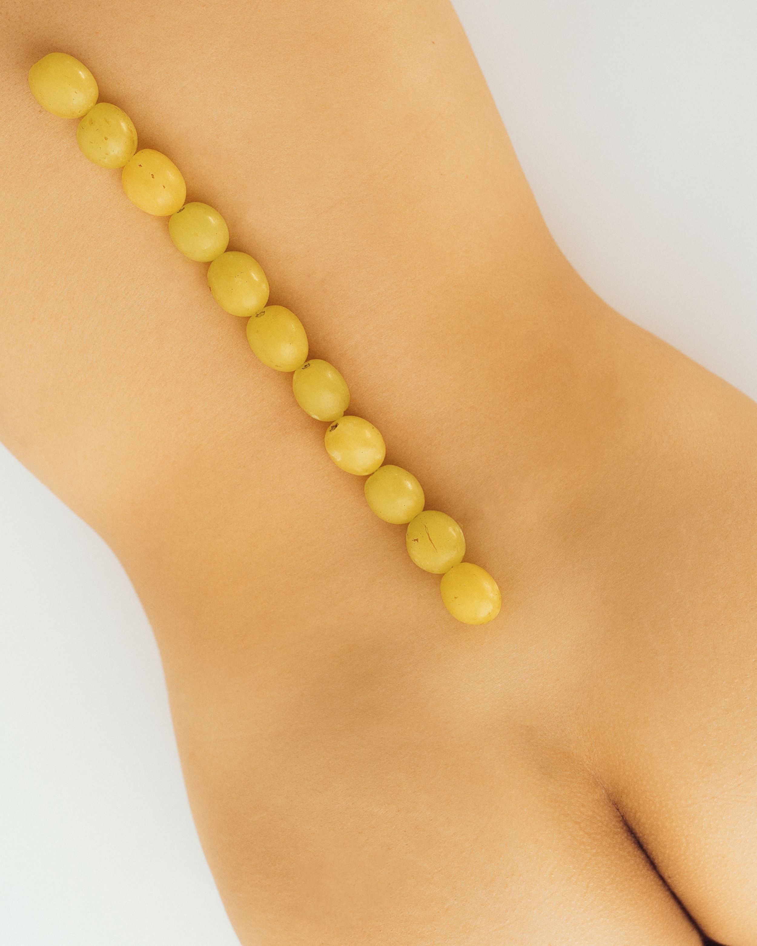 Yellow beaded strand necklace displayed diagonally against a neutral background, showcasing smooth round golden beads.