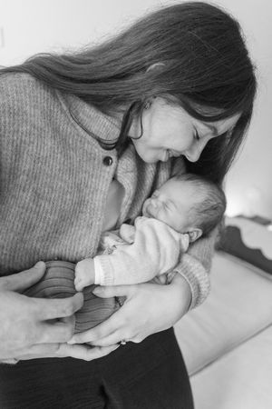 Black and white photo of a mother tenderly holding and gazing at her newborn baby.