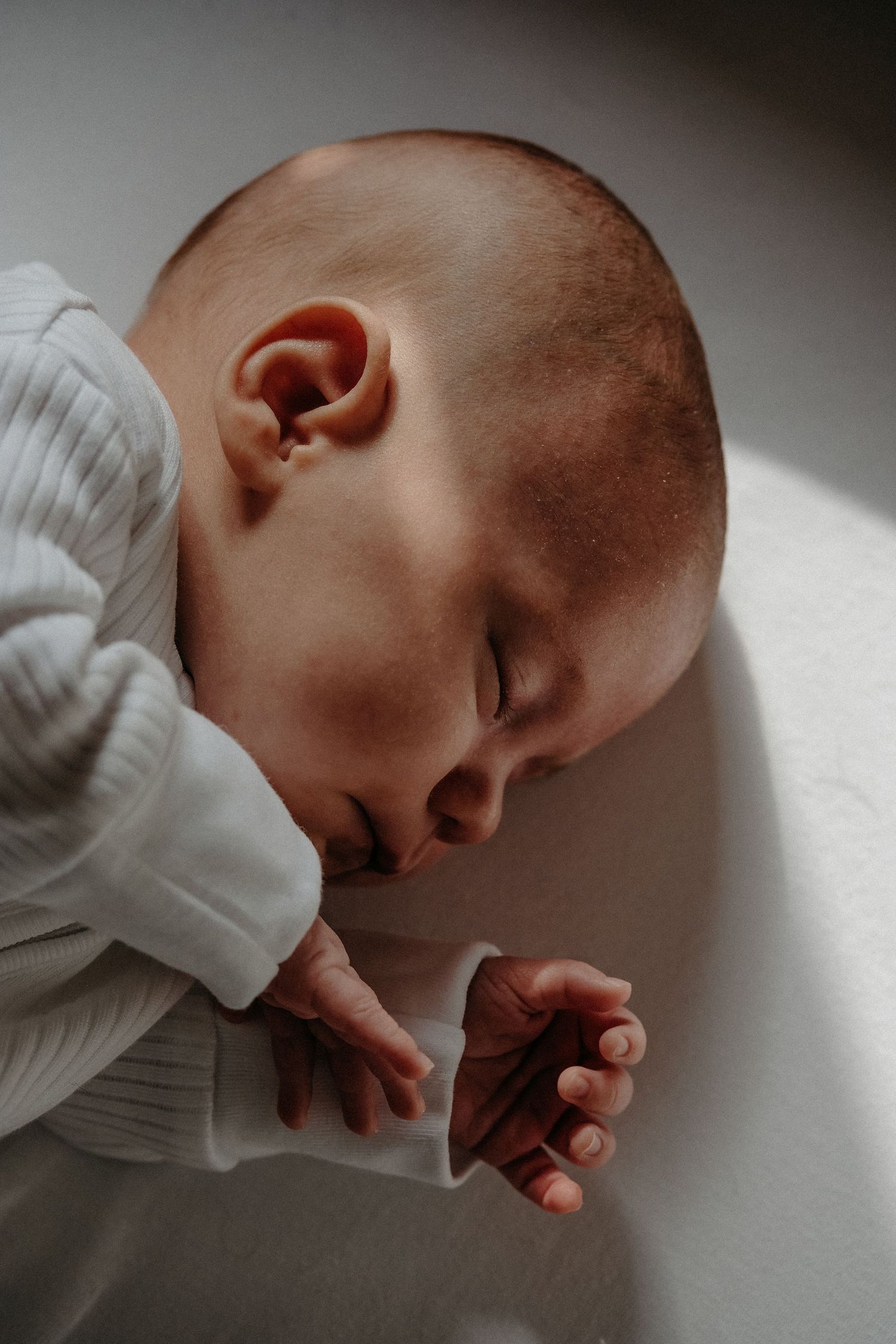 Light flows on newborn baby's face as they sleep in cot at newborn session in Northumberland