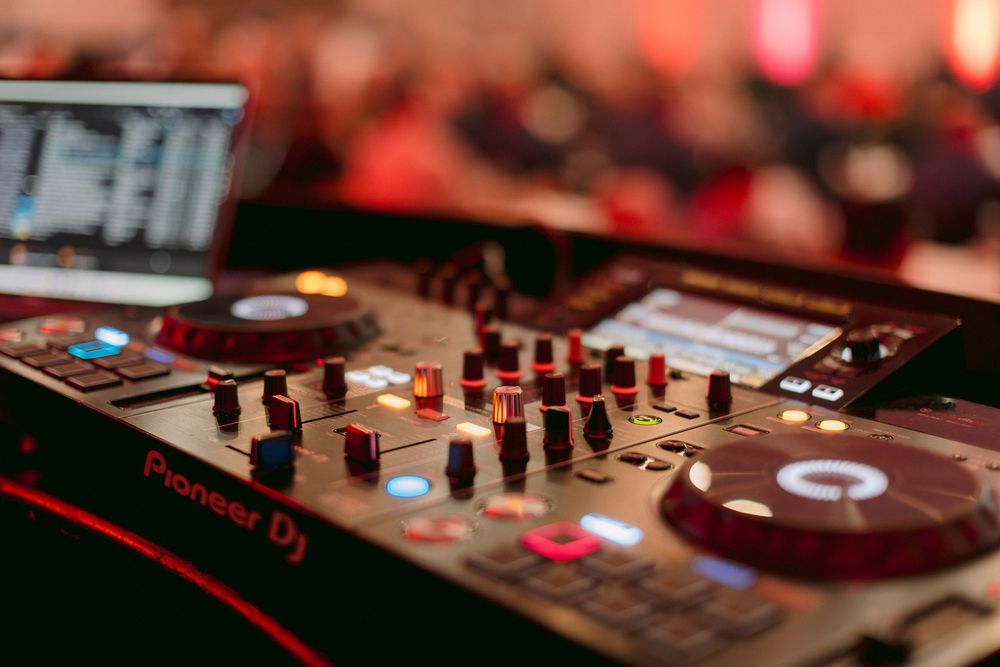 Pioneer DJ controller with colorful knobs and faders at a live event, professional DJ equipment close-up.