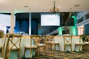 Elegant event venue setup with round tables, gold chairs, and Africa Designs branding on a projection screen.