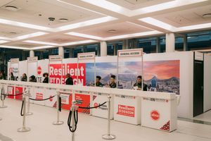 Resilient by Design conference registration area with red banners and stanchions in a modern venue.