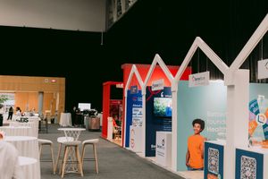 Exhibition booths with colorful house-shaped displays at a trade show event in a modern convention center.