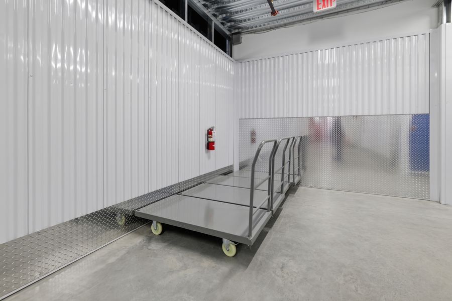 Loading area with metal flatbed carts near a large roll-up door in a self-storage facility.