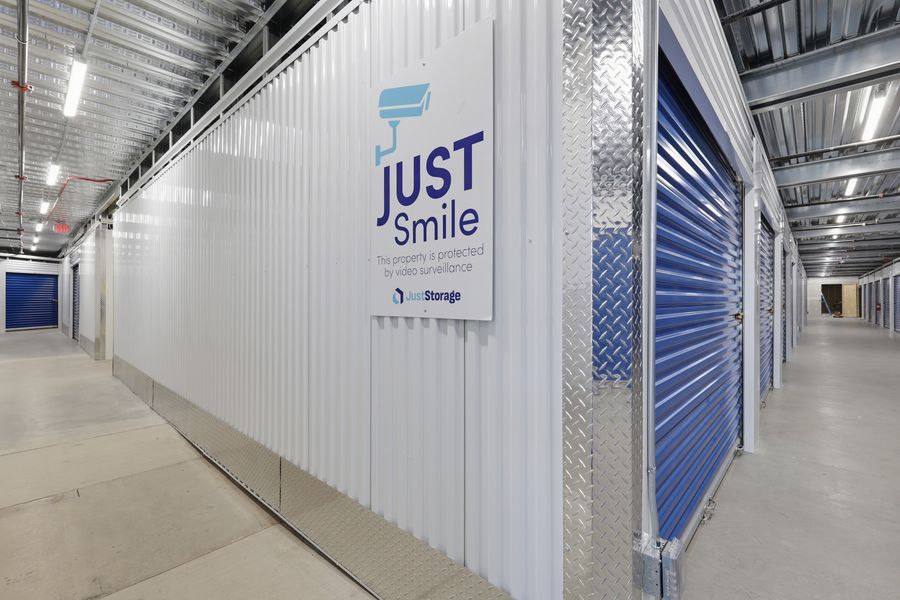 Indoor self-storage hallway featuring blue roll-up doors and a Just Smile CubeSmart storage unit sign.