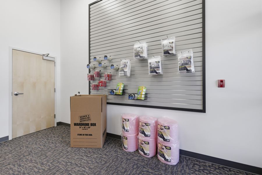 Storage facility retail area displaying moving boxes, bubble wrap rolls, and packing supplies mounted on a slatwall display panel.