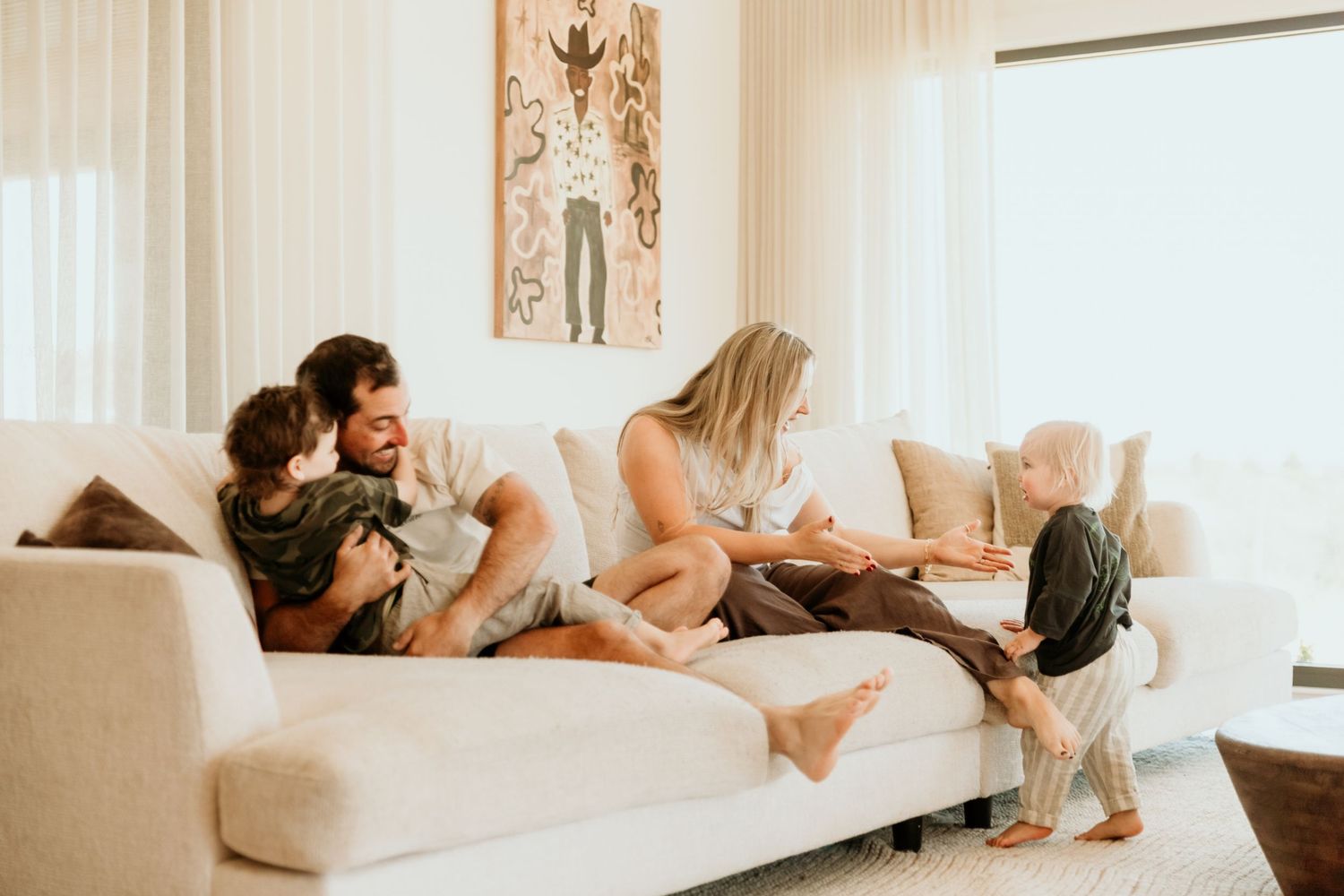 Happy family relaxing together on a white sofa in a bright living room.