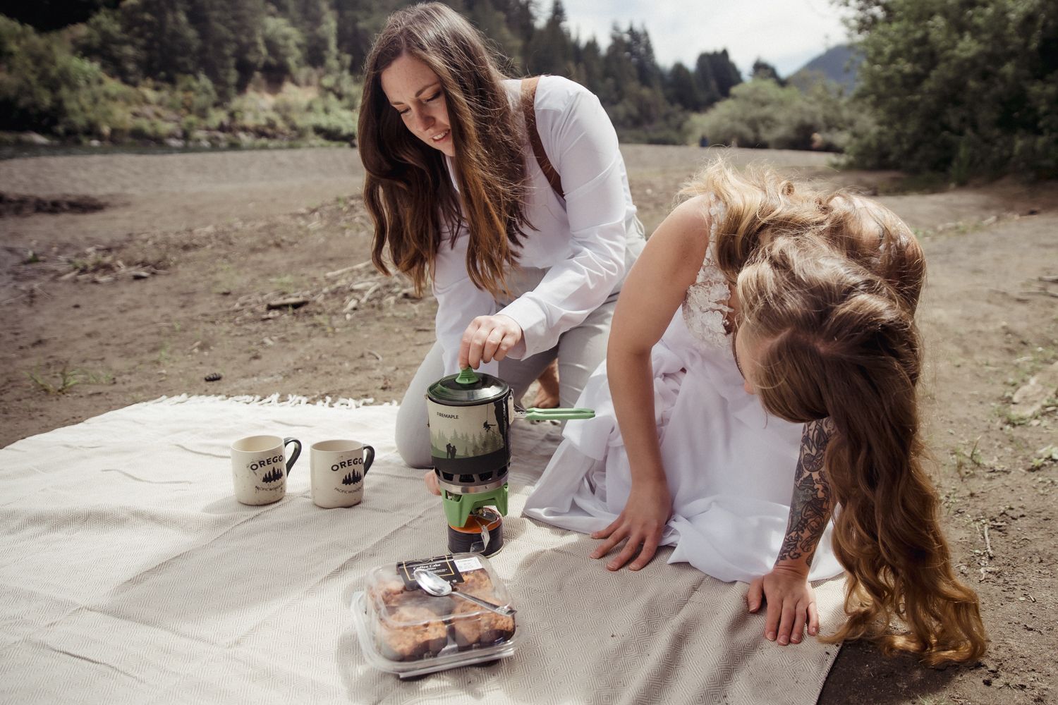 Two brides boil water in a backpacking stove on their elopement day
