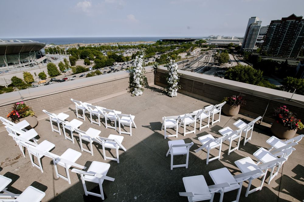 Rooftop wedding ceremony setup with white chairs arranged in rows overlooking a city skyline and waterfront.