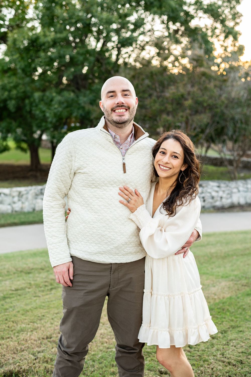 Couple wearing cream and brown outfits posing for casual outdoor photos in a grassy setting.